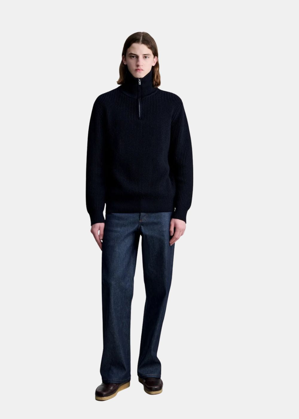 Mannequin homme portant le pull camionneur en laine noir A.P.C. col montant fermé avec un jean brut.