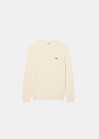 Packshot de face du pull col rond Lacoste en jersey de coton biologique crème avec crocodile brodé.
