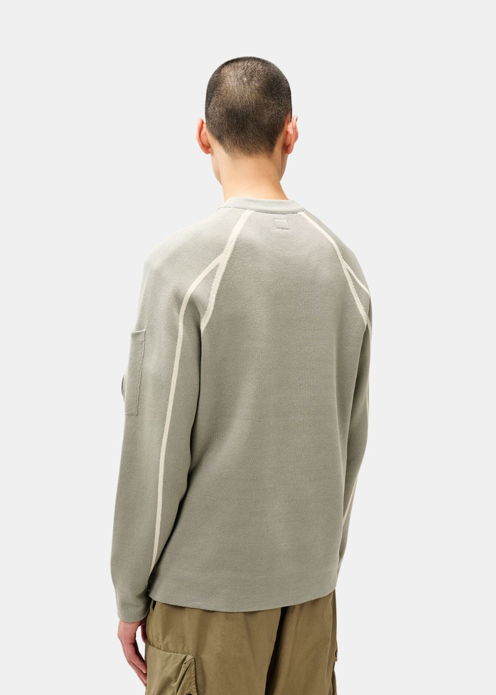 Vue de dos du mannequin montrant les coutures raglan contrastées du pull C.P. Company gris.