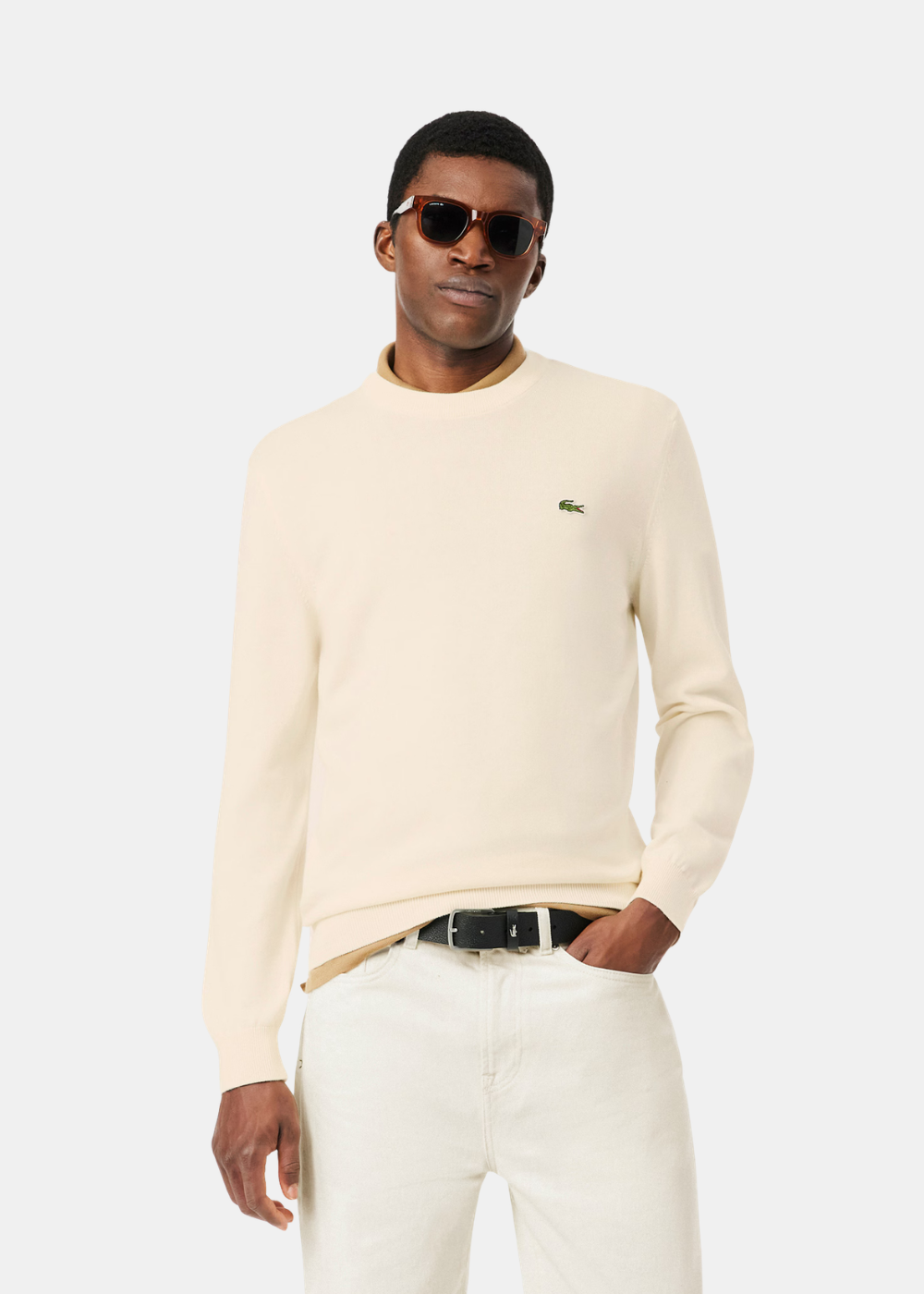 Mannequin portant le pull col rond Lacoste crème en jersey de coton sur une chemise.