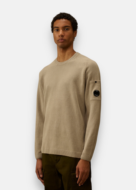Pull C.P. Company beige en maille chenille porté avec poche et détail de lentille sur la manche