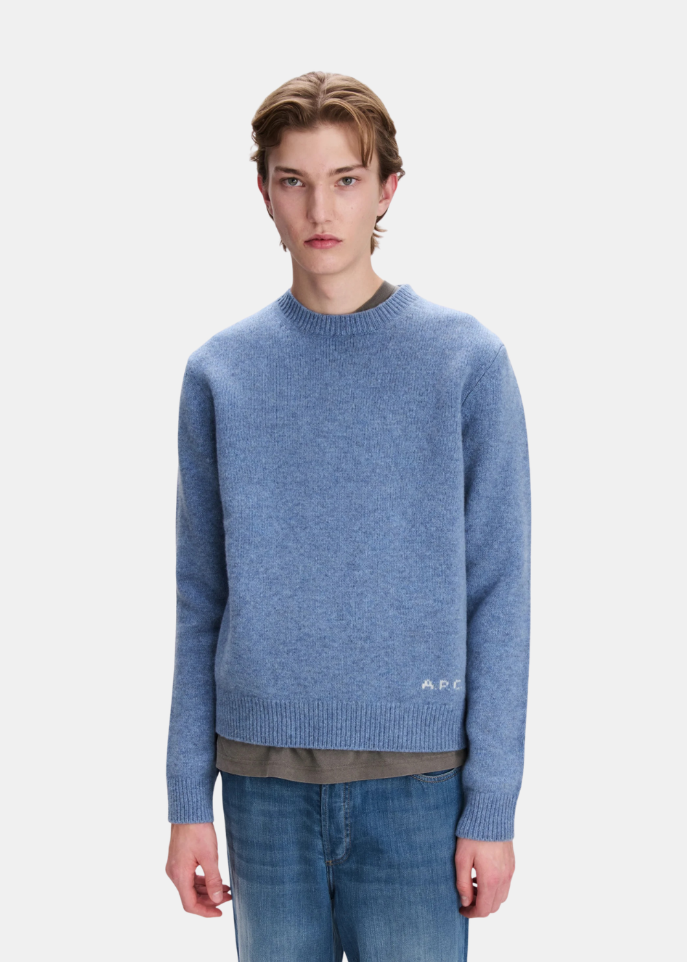 Mannequin homme de face portant le pull en maille bleu chiné A.P.C. col rond avec discret logo A.P.C. blanc brodé sur la base gauche