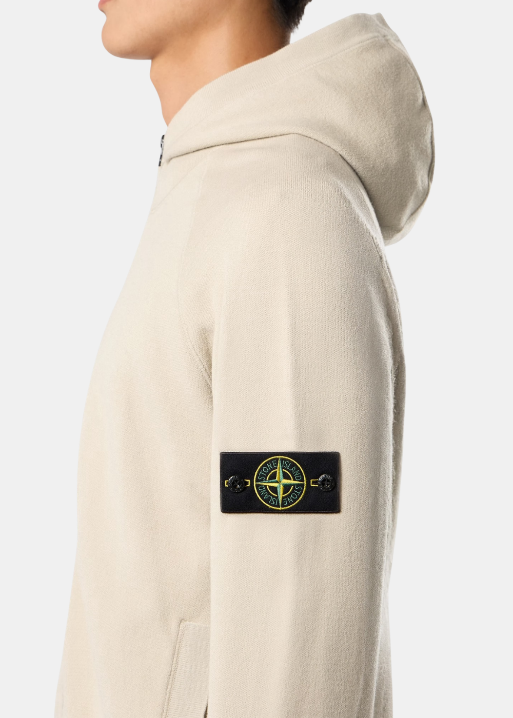 Gros plan sur le badge boussole Stone Island bouttonné sur la manche gauche du pull zippé à capuche sable