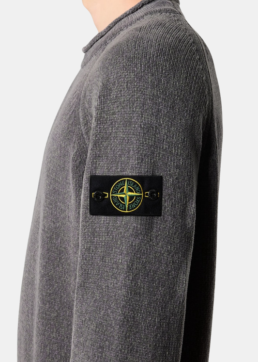 Gros plan sur le badge Compass Stone Island boutonné sur la manche d'un pull en maille chenille gris
