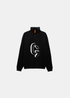 Packshot à plat de face du pull Gertrude noir à col demi-zip, motif logo CG en intarsia blanc et tirette orange