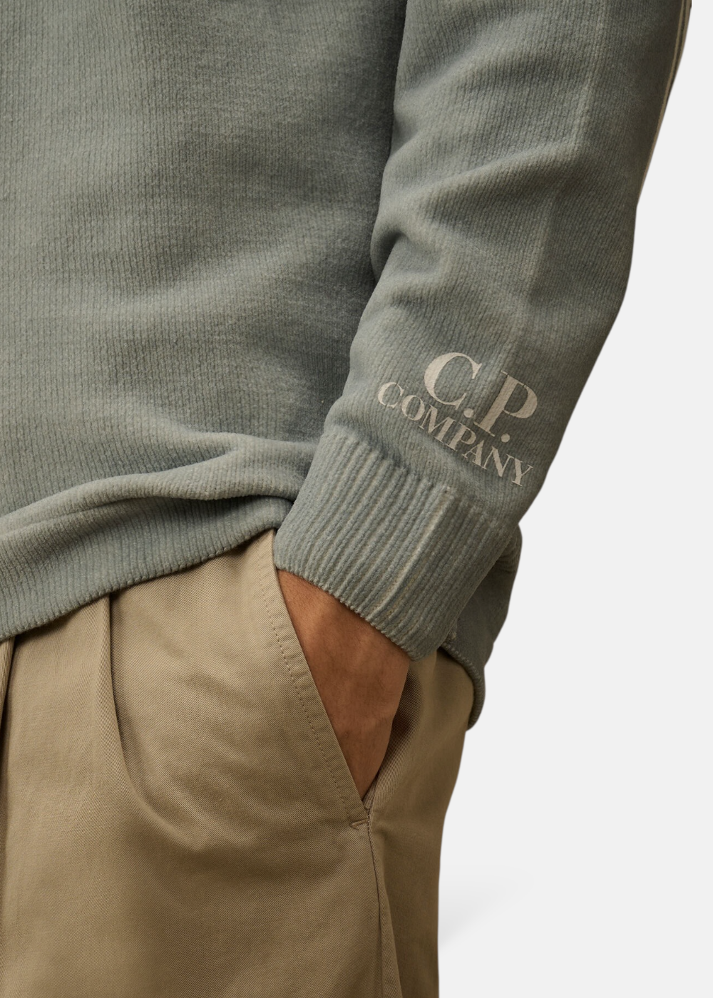 Détail des finitions du poignet et du col du pull C.P. Company bleu, illustrant la douceur de la chenille