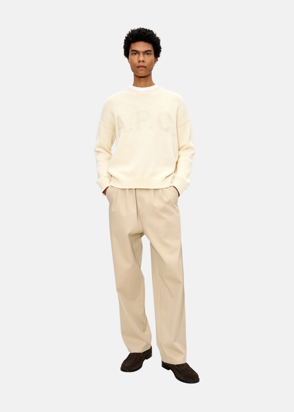 Look complet avec pull crème A.P.C. à logo et pantalon chino beige, porté par un mannequin de face.