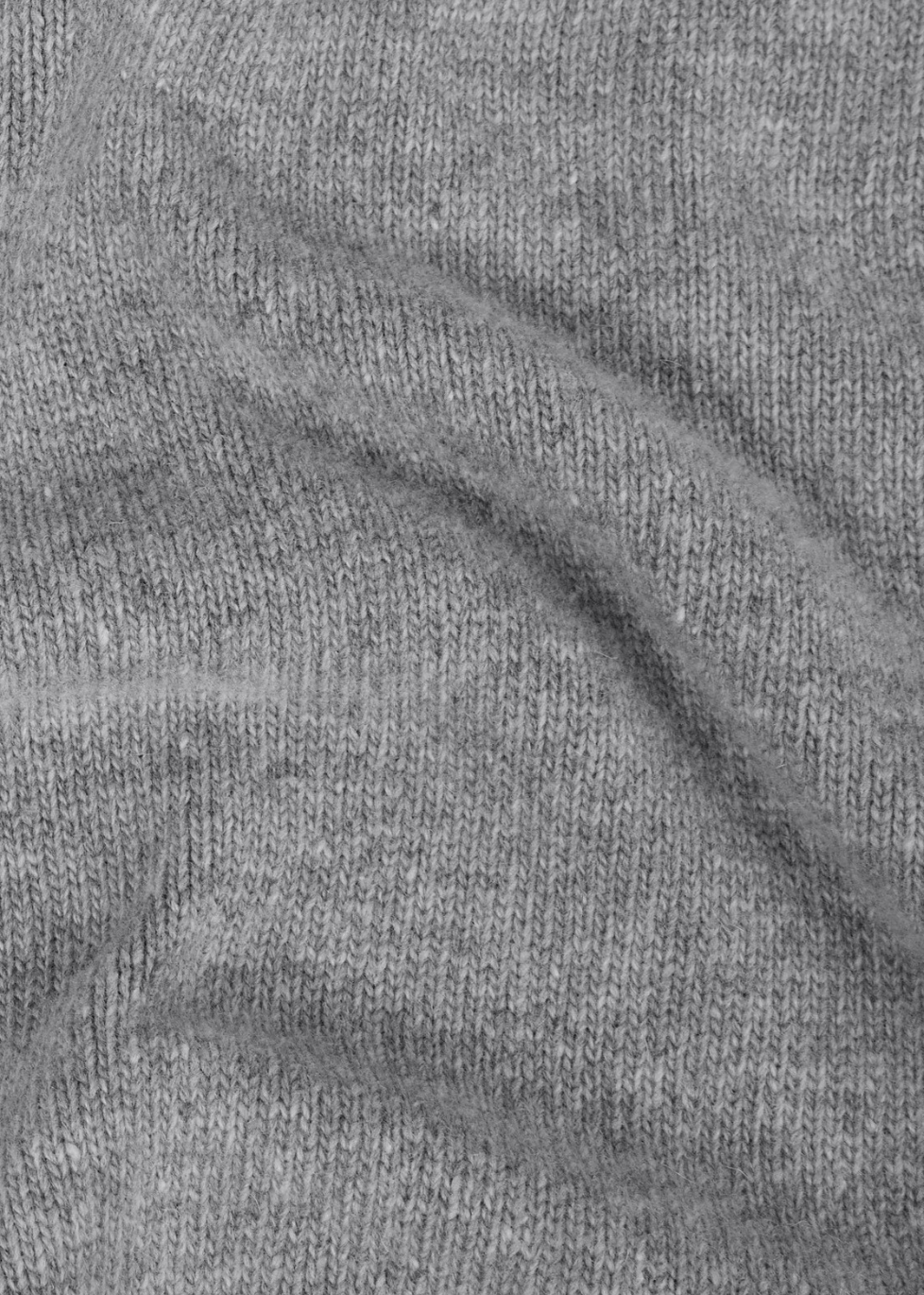 Gros plan texturé sur la maille douce et l'aspect chiné d'un pull en laine de agneau gris Stone Island.