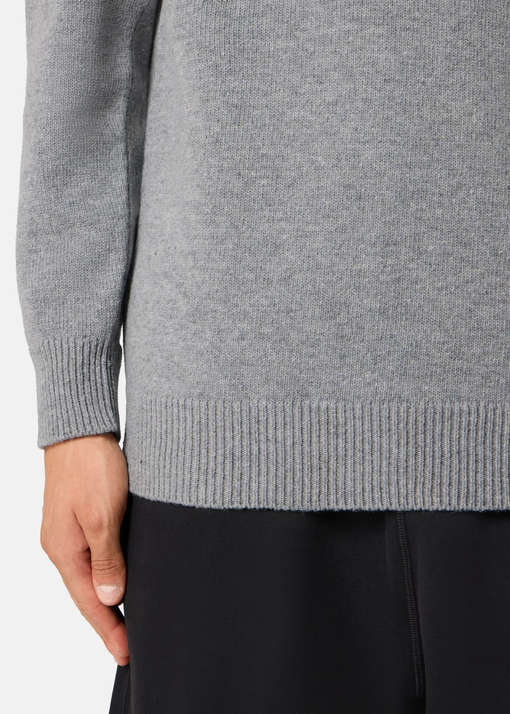 Zoom sur les finitions côtelées du bas et du poignet d'un pull gris chiné Stone Island en laine de agneau.