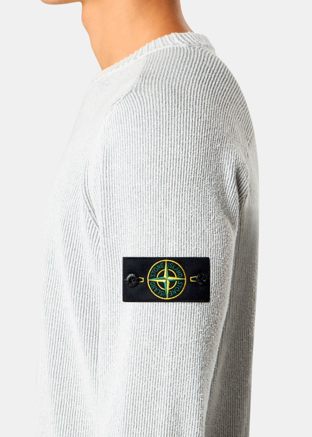 Vue de profil d'un pull gris perle Stone Island porté, mettant en avant le badge boussole amovible.