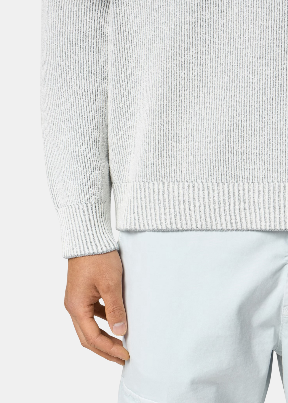 Gros plan sur le bas d'un pull gris perle Stone Island porté avec un bas clair.