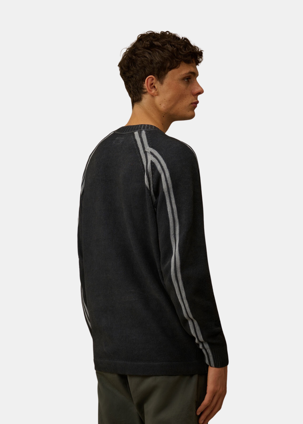Mannequin homme vu de dos de trois-quarts portant le pull en maille chenille marine C.P. Company, mettant en valeur la continuité des doubles rayures grises le long des manches raglan