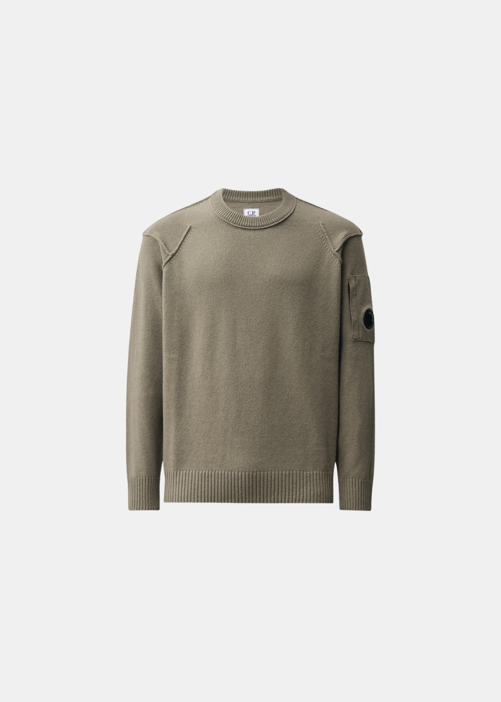 Packshot de face sur fond gris d'un pull col rond C.P. Company en laine lambswool GRS couleur kaki, avec détails de coutures apparentes aux épaules et poche à lentille sur la manche gauche