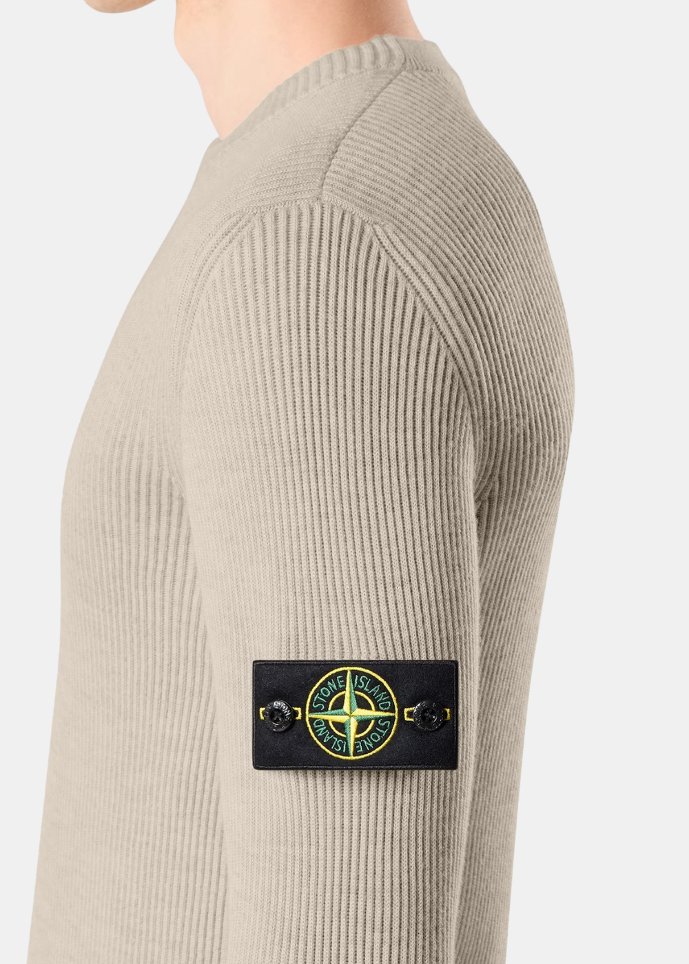 Gros plan sur le badge Compass Stone Island sur la manche d'un pull en laine côtelée sable porté