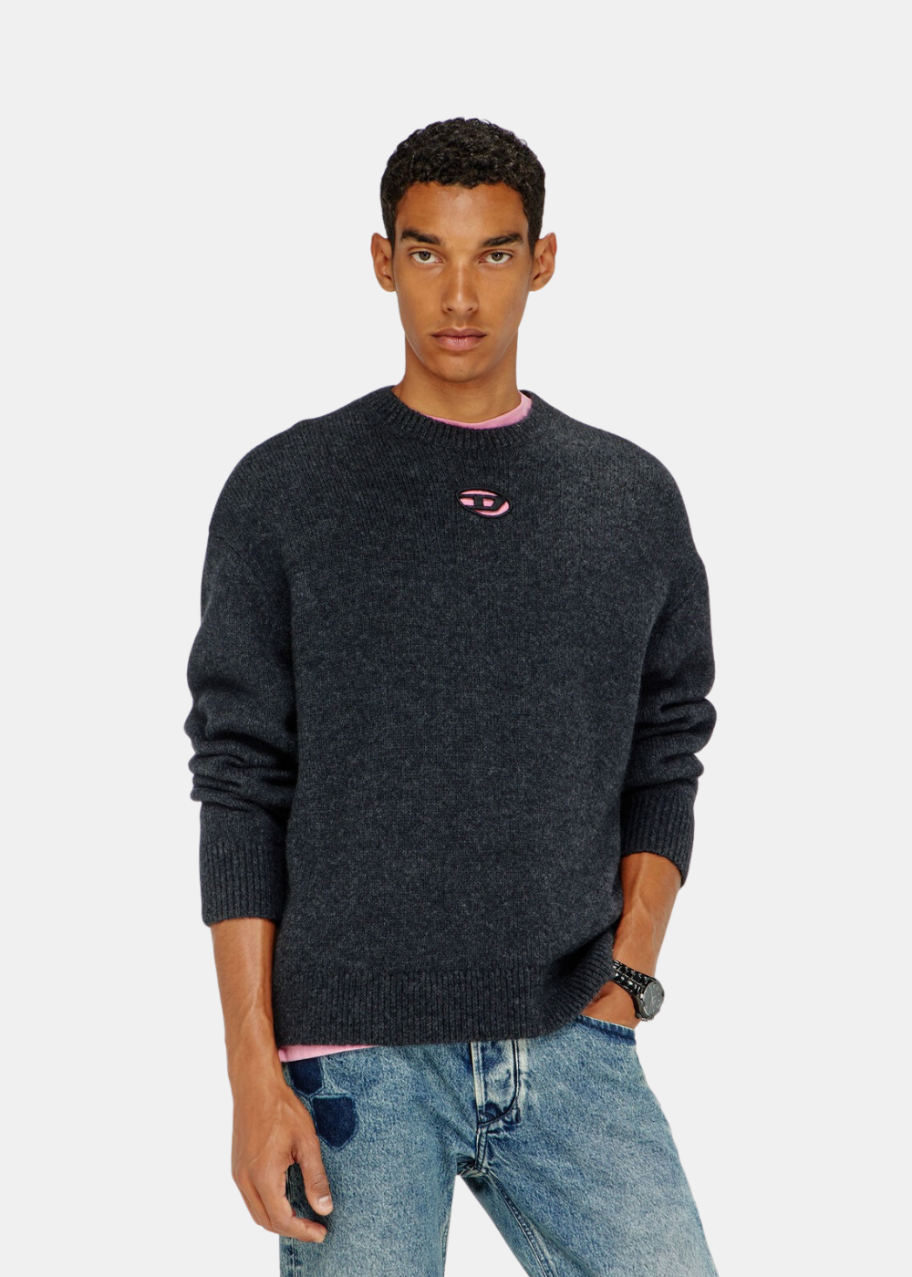 Mannequin homme de face portant le pull en maille noir Diesel avec logo Oval D rose et col t-shirt rose apparent