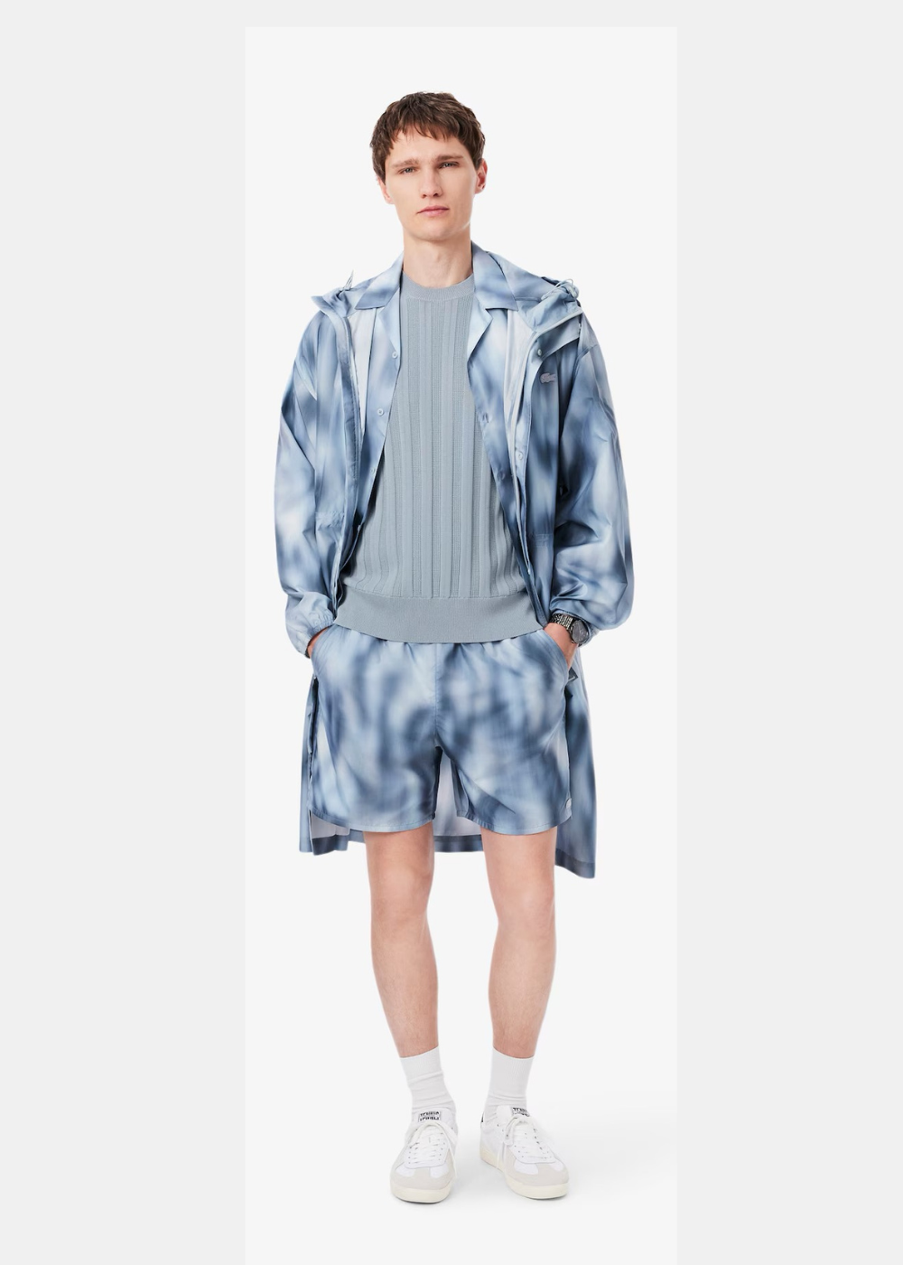 Mannequin homme portant le pull bleu clair Lacoste sous une veste et un short assortis à motif imprimé