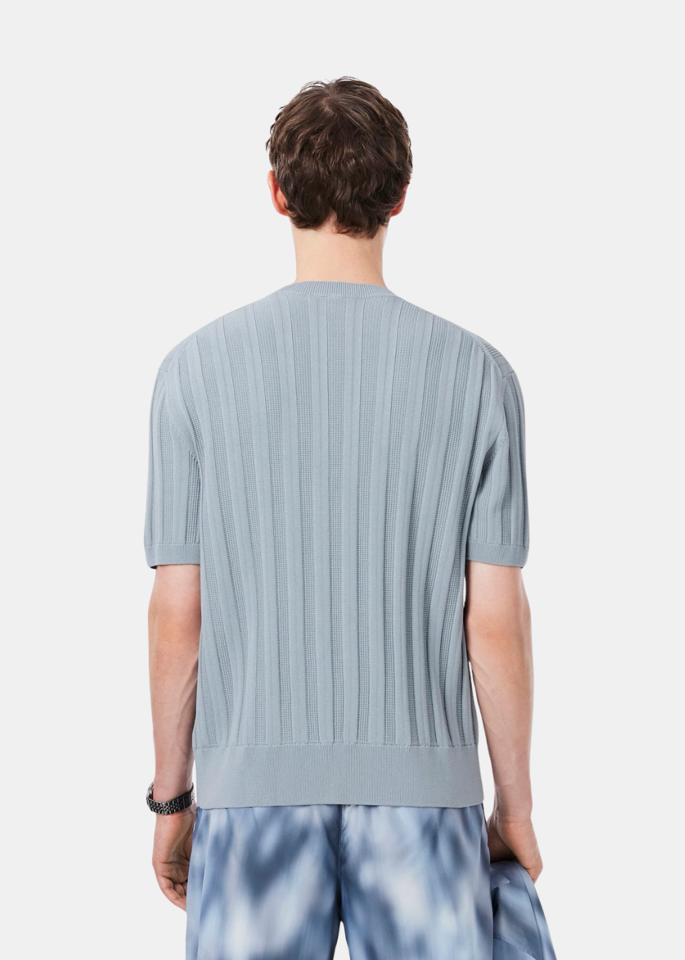 Mannequin homme vu de dos portant le pull à manches courtes bleu clair texturé Lacoste