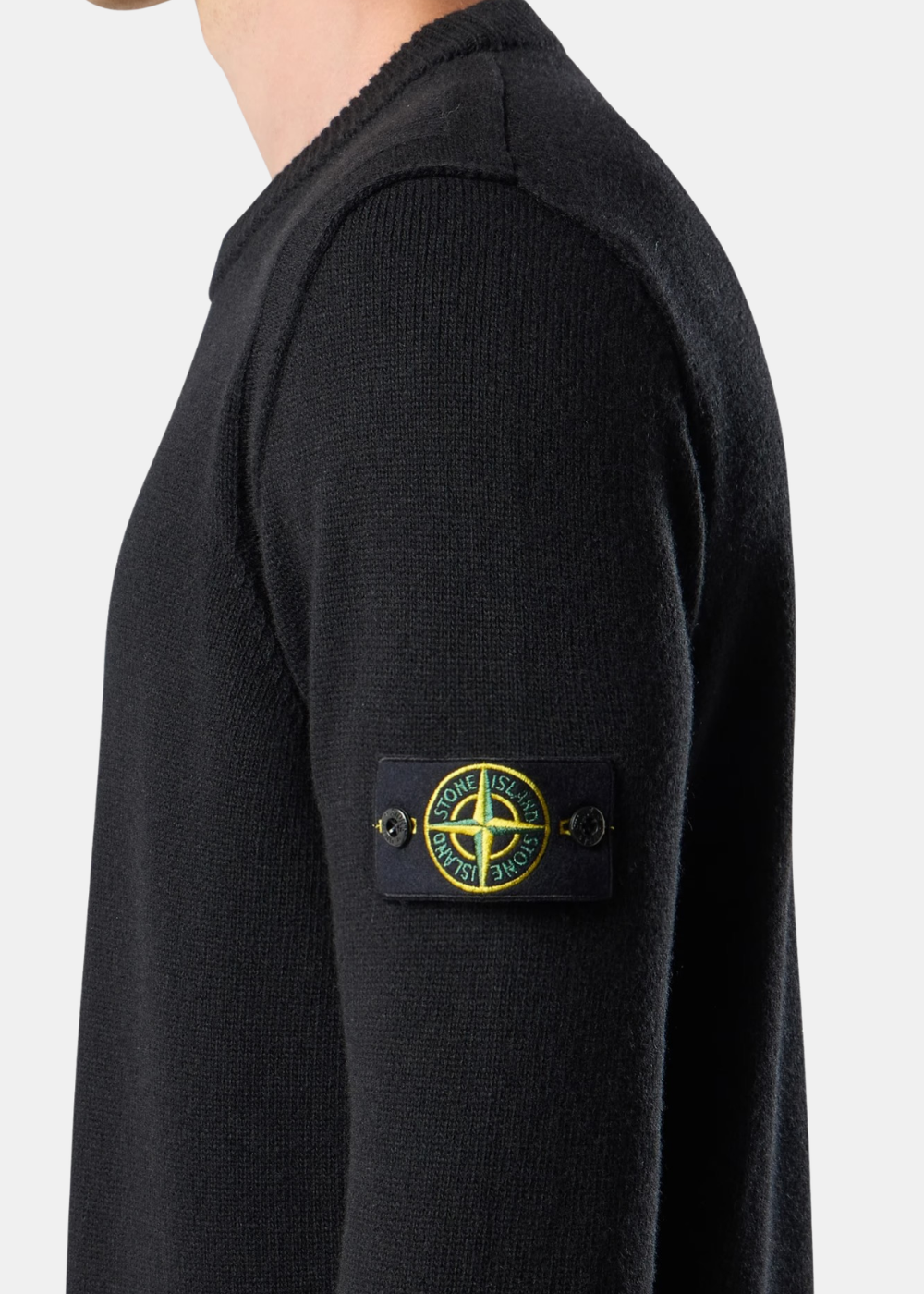 Porté de profil mettant en valeur le badge boussole emblématique Stone Island boutonné sur la manche gauche du pull noir.