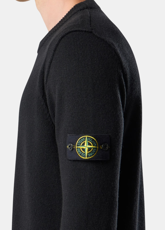 Porté de profil mettant en valeur le badge boussole emblématique Stone Island boutonné sur la manche gauche du pull noir.