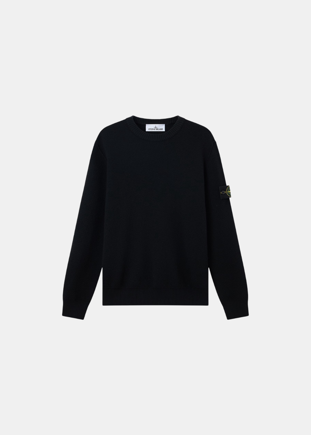 Pull noir en pure laine posé à plat, vue de face (12.jpg), avec col rond et le badge boussole Stone Island boutonné sur la manche gauche.