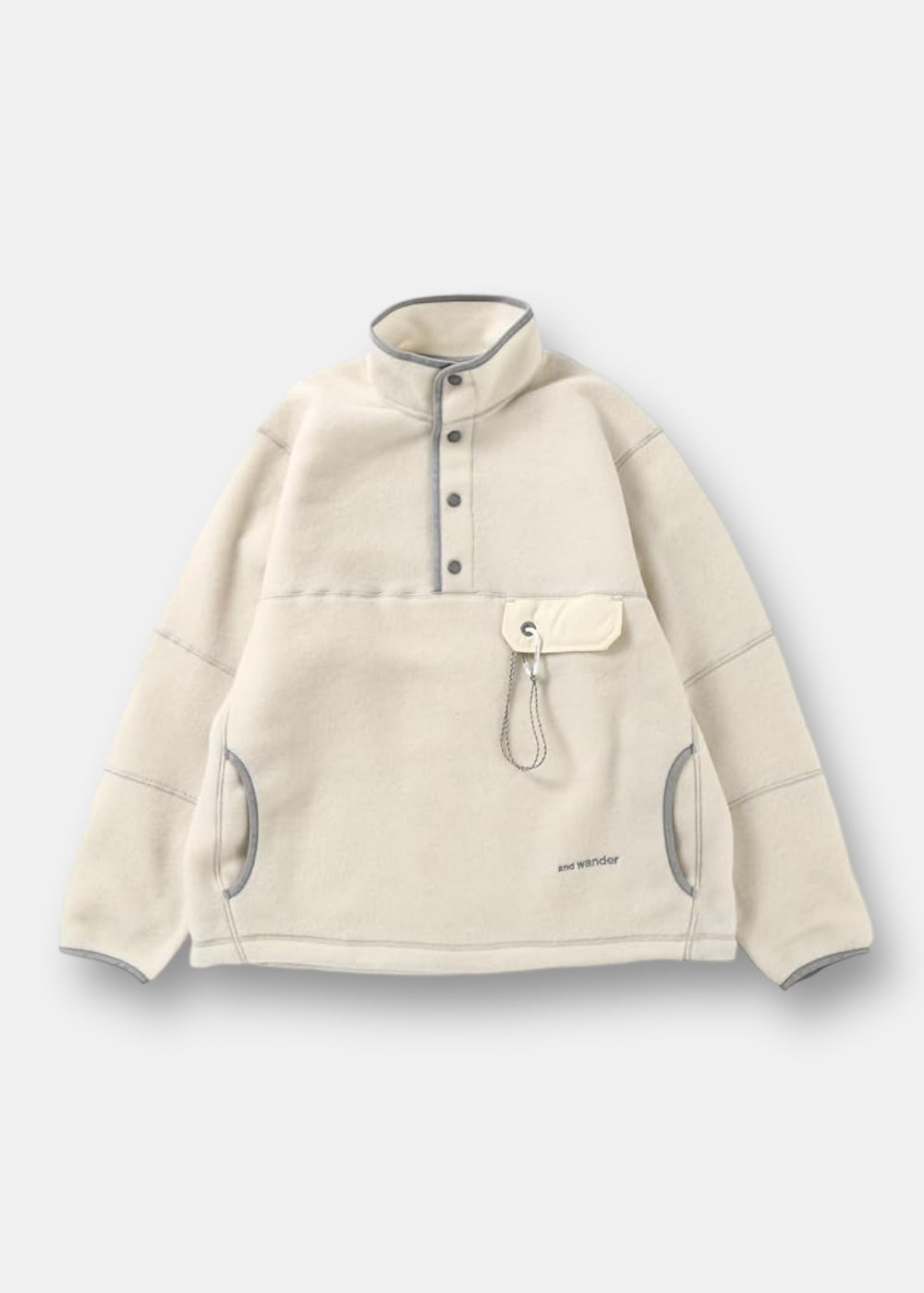 Pull polaire And Wander en laine, écru, col montant boutonné, poche poitrine avec mousqueton, isolation pour l'outdoor.