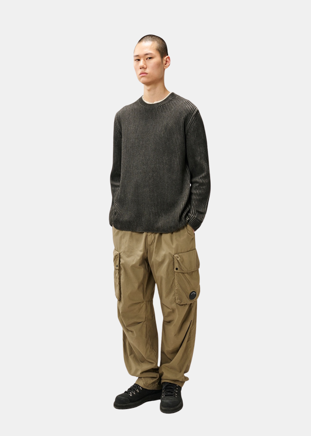 Silhouette complète portée du pull ras-de-cou C.P. Company gris assorti à un pantalon cargo beige et chaussures noires