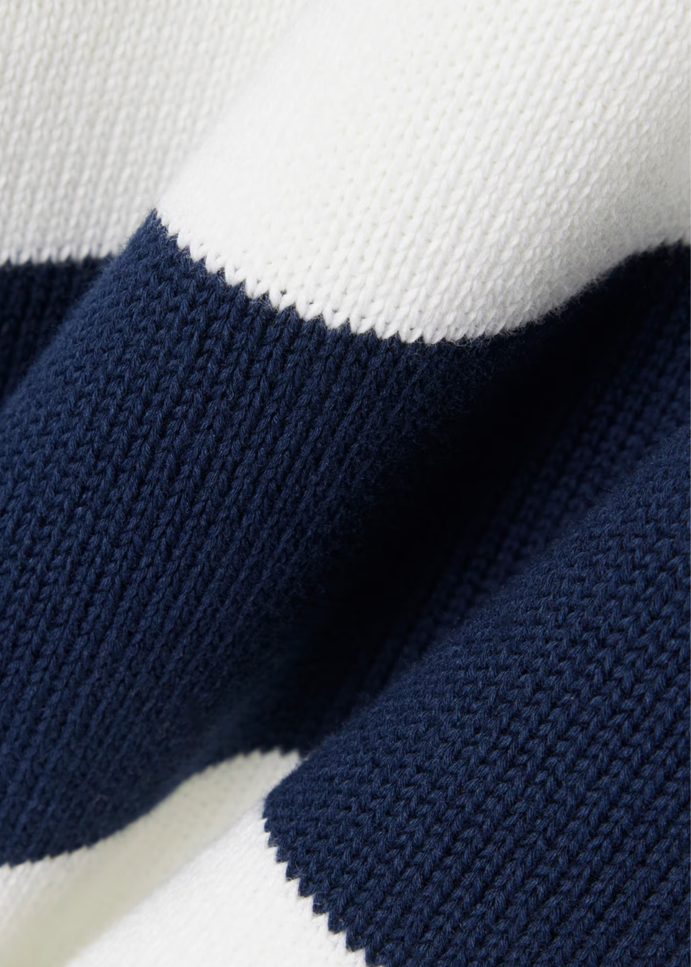 Gros plan sur la texture de la maille tricotée rayée marine et blanche du pull Lacoste