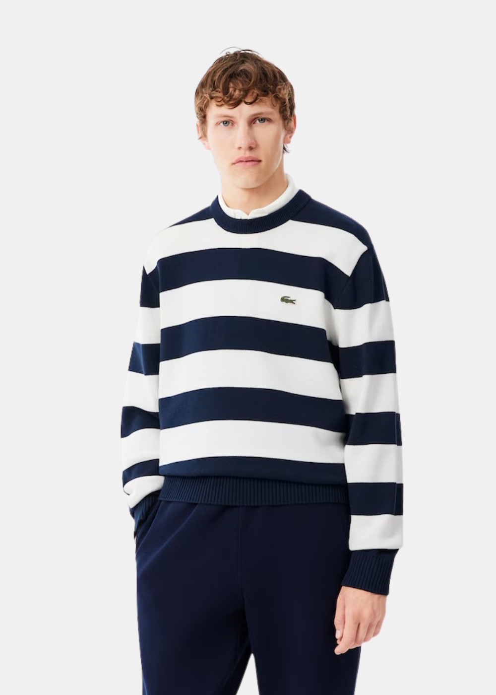 Mannequin homme de face portant le pull rayé marine et blanc Lacoste sur une chemise blanche
