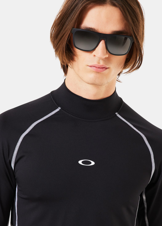 Gros plan sur le col montant, les coutures plates grises et le logo ellipse Oakley sur la poitrine.