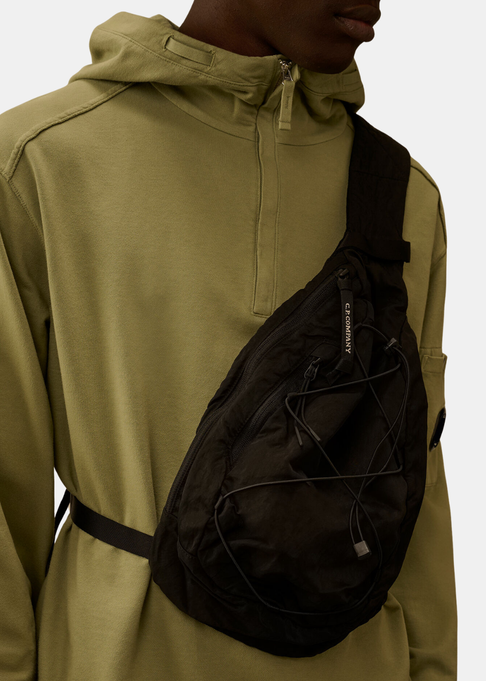 Gros plan sur le sac crossbody C.P. Company en nylon noir montrant la fermeture zippée et les détails techniques.