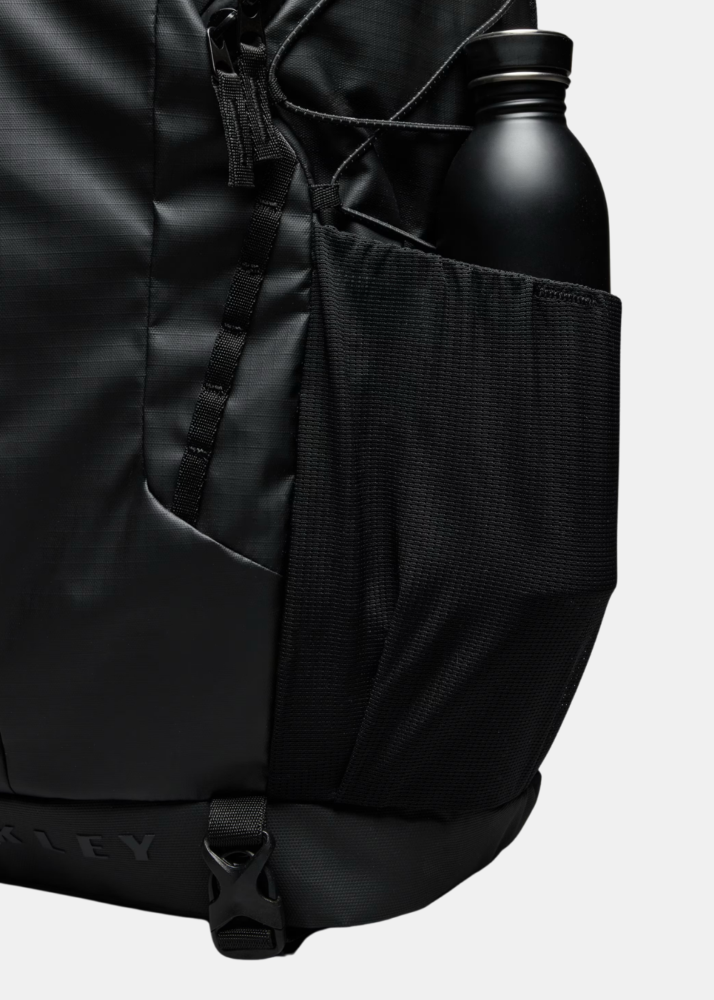 Gros plan sur la poche latérale en filet du sac à dos Oakley Terraquest 29L noir contenant une gourde métallique