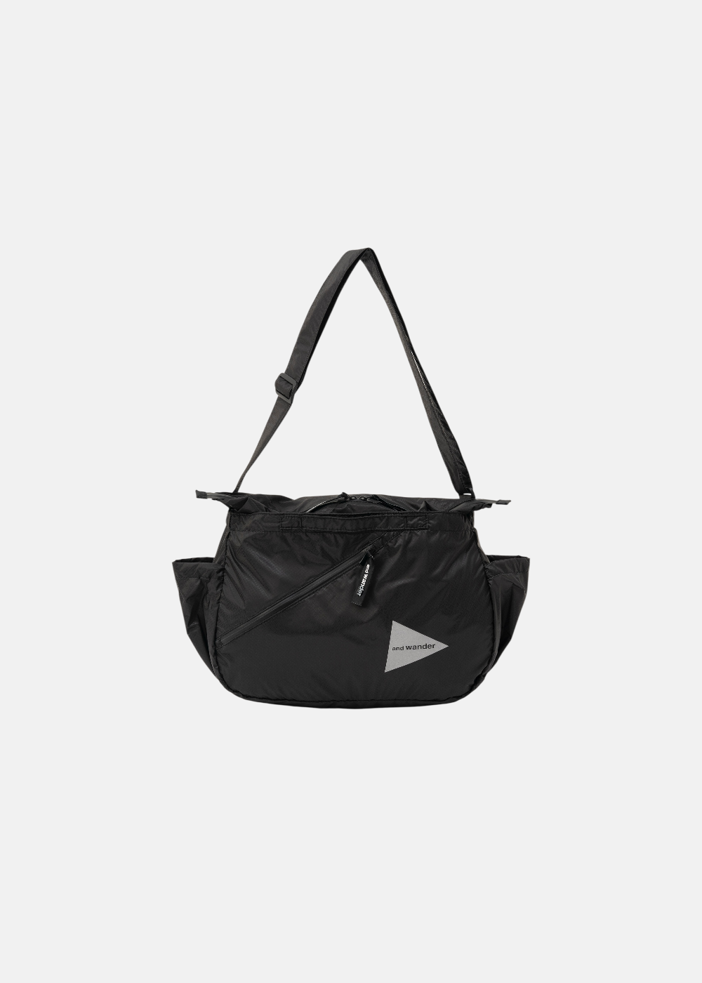 Vue de face du sac bandoulière noir And Wander avec sangle, zip central et logo triangulaire sur fond blanc