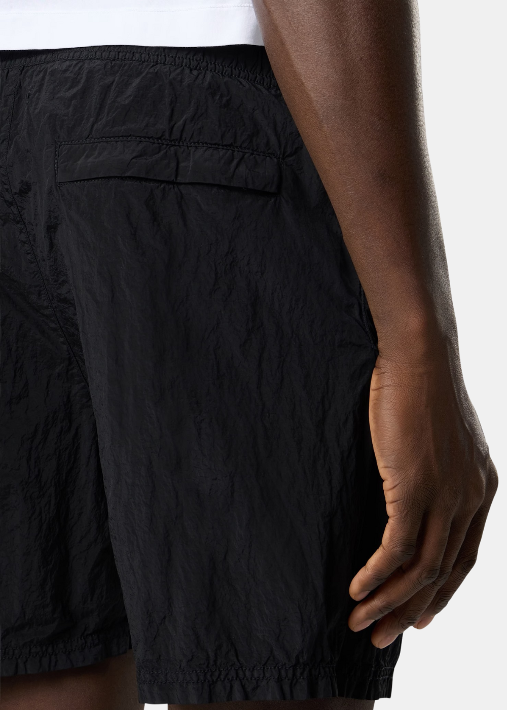Zoom sur l'arrière du short de bain porté, mettant en évidence la texture du nylon metal et la poche.