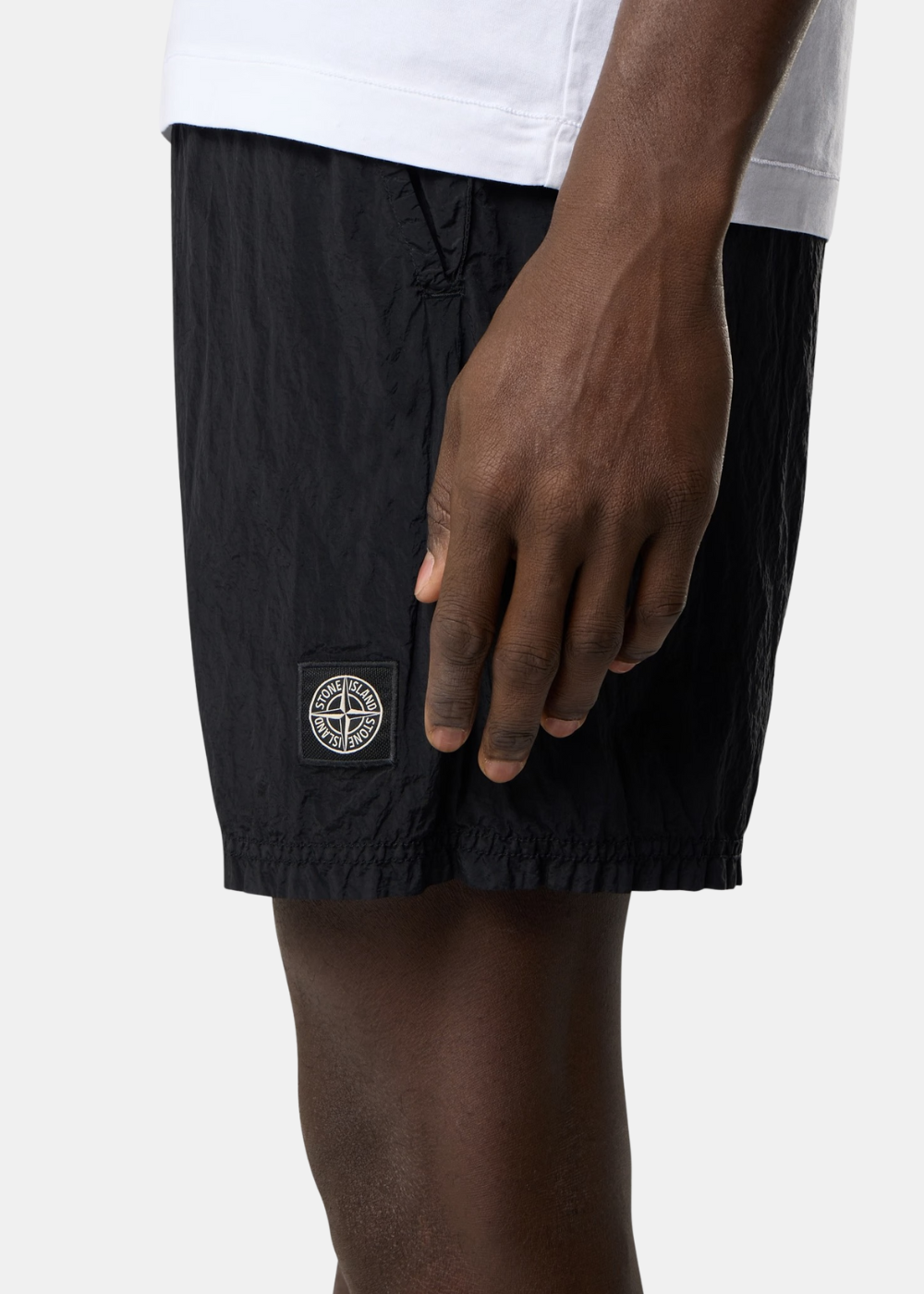 Gros plan sur le patch logo Stone Island brodé sur la matière technique en nylon noir.