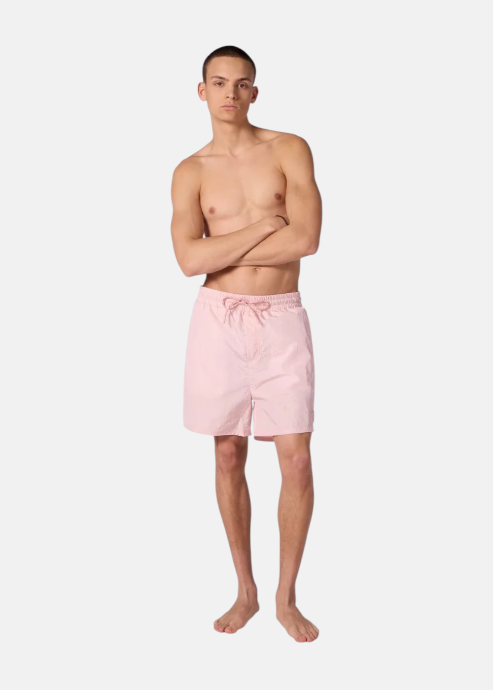 Homme portant le short de bain rose Gertrude de face, bras croisés, montrant la coupe et la matière.