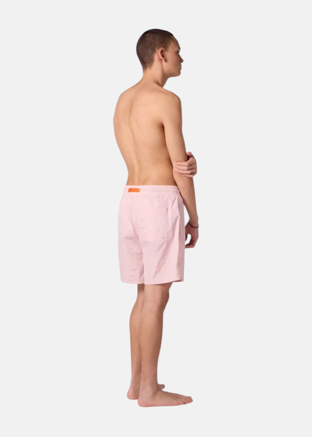 Vue de trois-quarts dos d'un homme portant le short de bain rose Gertrude montrant la poche arrière.