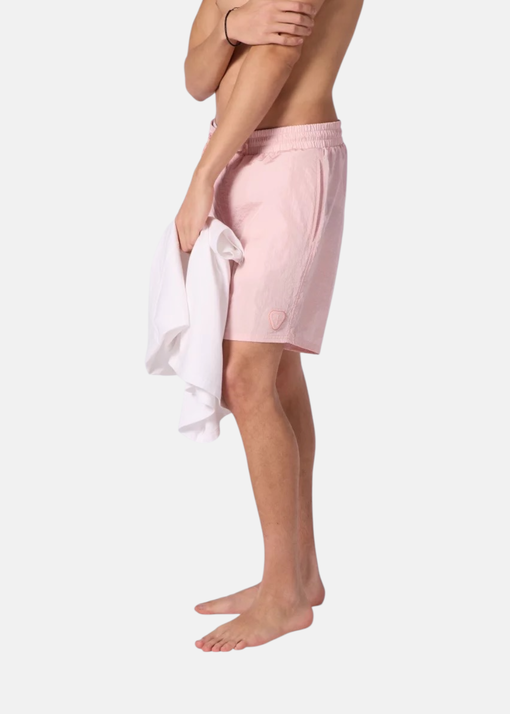 Vue de profil d'un homme portant le short de bain rose Gertrude, focus sur la jambe et le logo écusson.