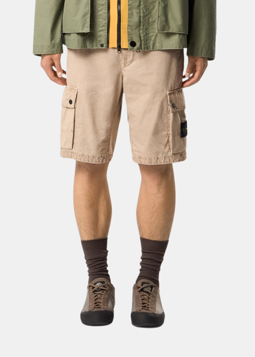 Short cargo beige Stone Island porté de face avec un look complet comprenant veste kaki et baskets marron.