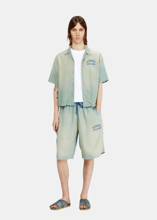 Look complet homme avec chemise assortie et short en denim bleu effet sali porté de face.