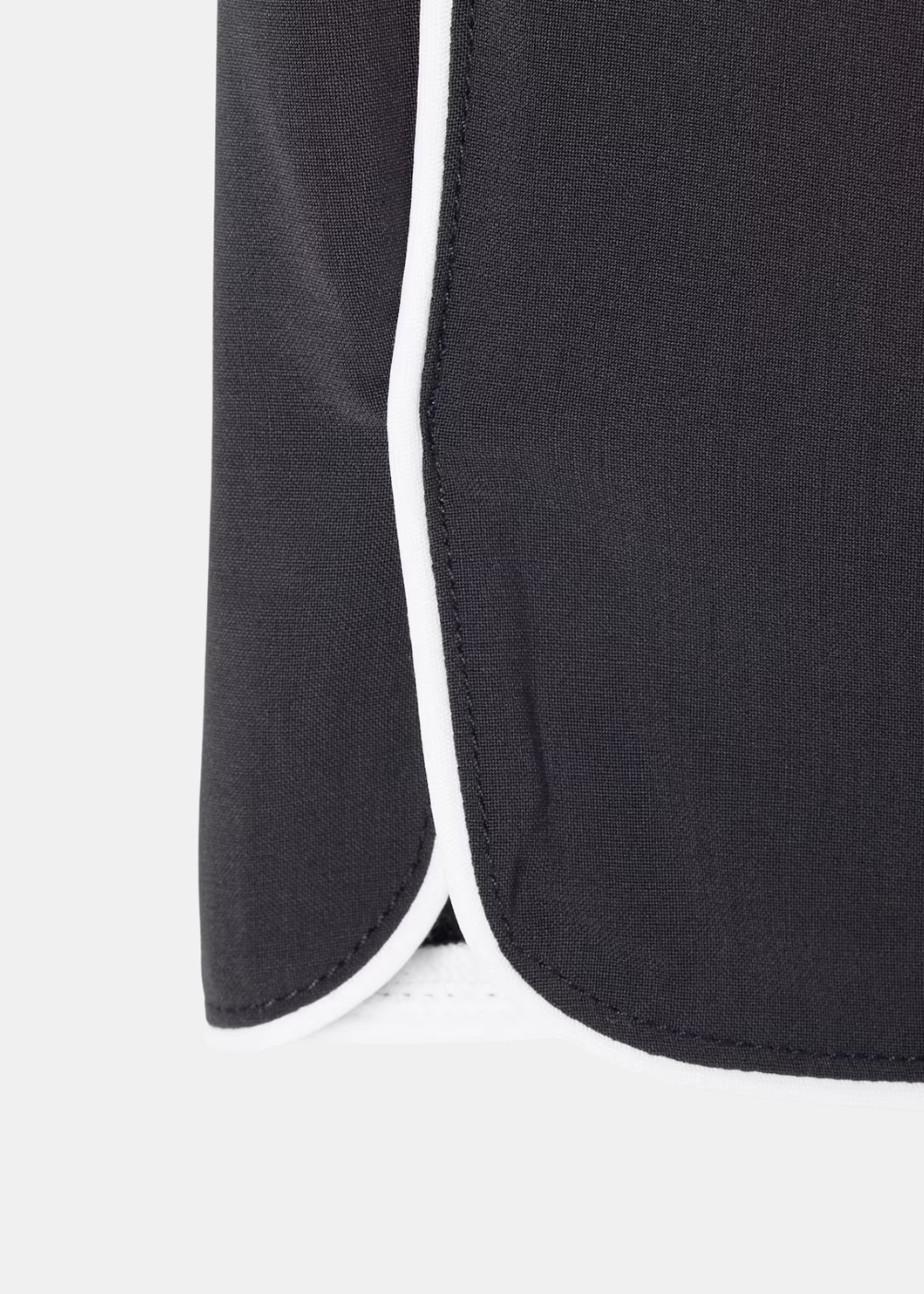 Zoom sur le bas de jambe arrondi du short Lacoste gris avec une finition passepoilée blanche contrastante.