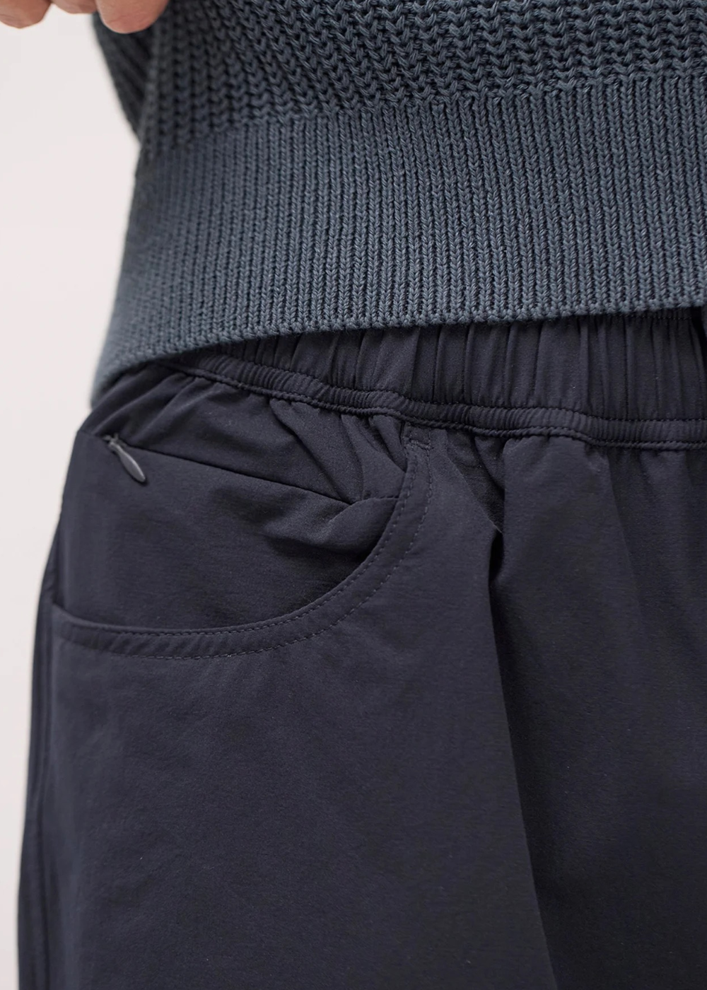 Gros plan sur la taille élastiquée et la poche latérale zippée du short technique marine Norse Projects porté par un mannequin.