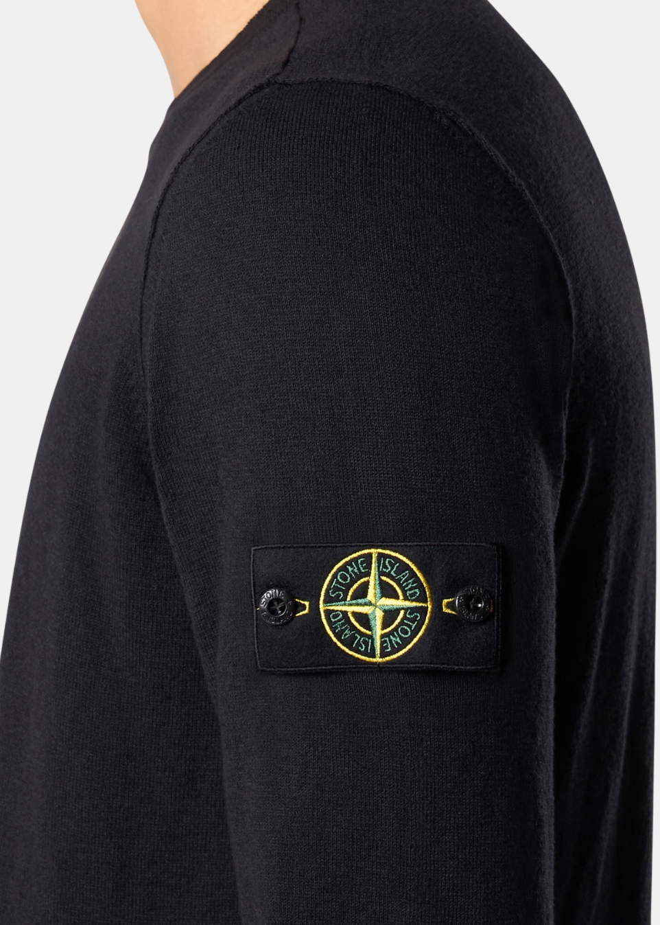Détail du badge Stone Island sur la manche gauche d'un pull noir en coton organique et nylon.