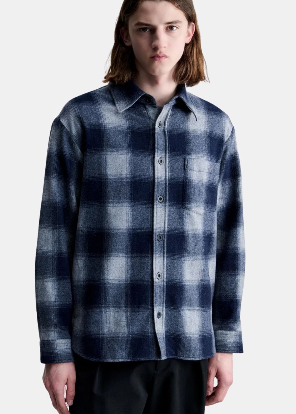Mannequin homme portant la surchemise A.P.C. Malaury à carreaux bleu marine et gris boutonnée.