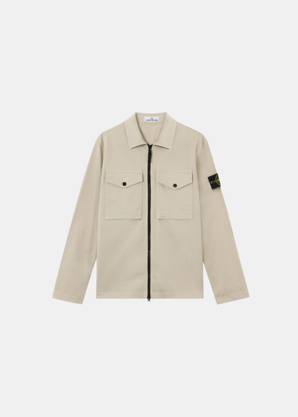 Packshot de face d'une surchemise zippée en satin de coton stretch beige Stone Island dotée de deux poches poitrine et d'un badge sur la manche gauche.