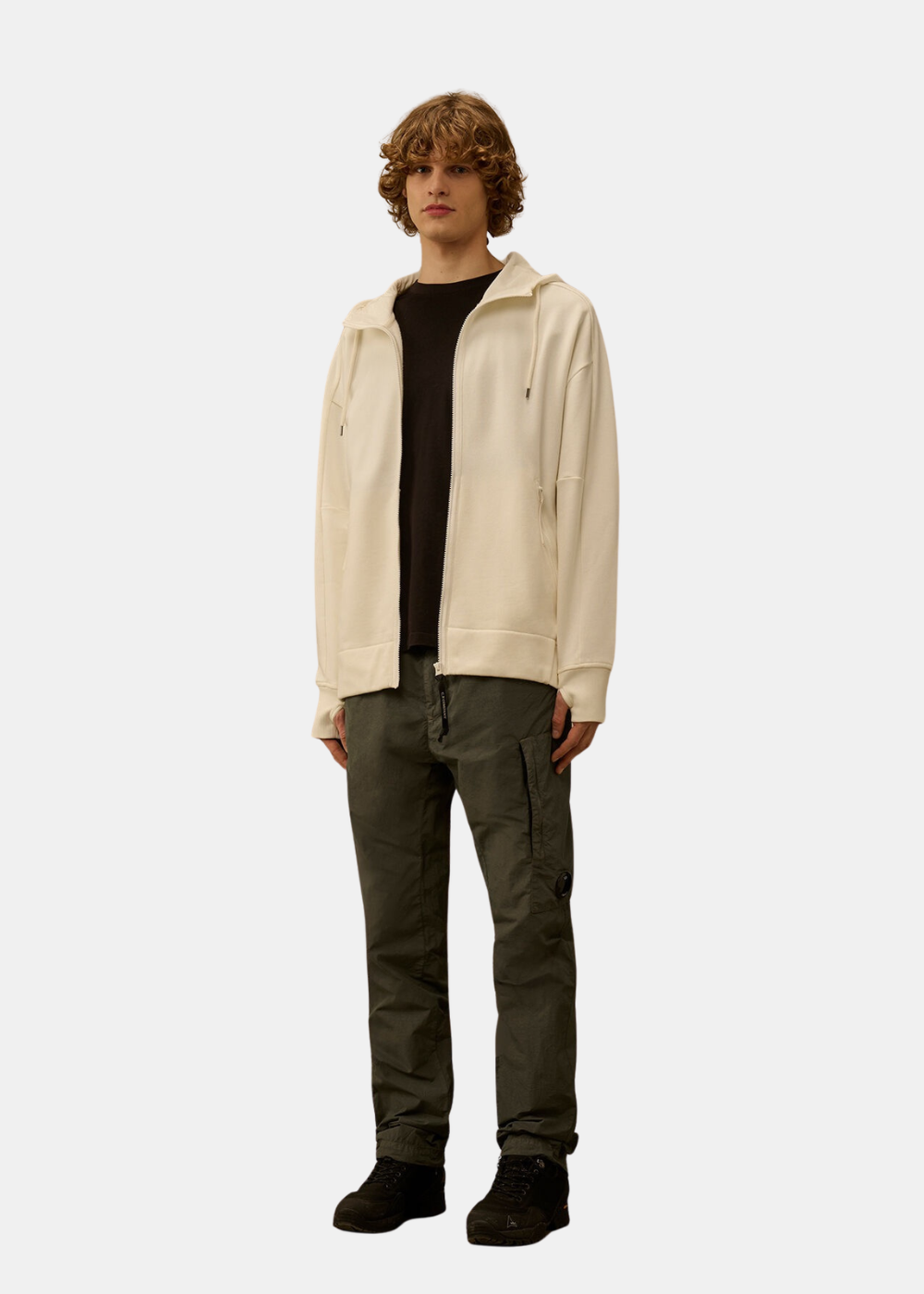 Look complet homme avec sweat zippé blanc cassé, t-shirt noir, pantalon cargo vert et bottines.