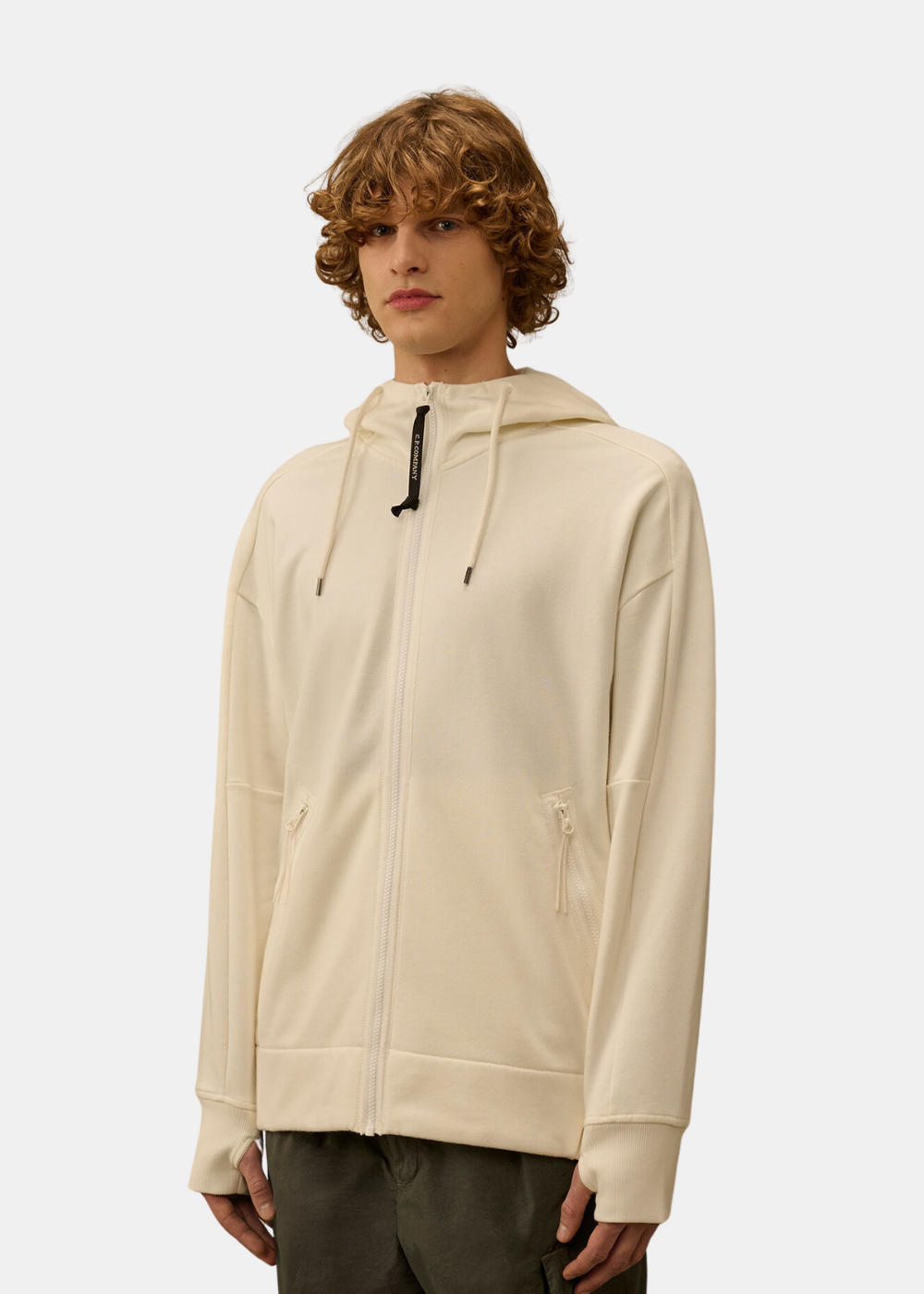 Sweat zippé blanc cassé C.P. Company porté de face avec capuche et tirette de zip logotée.