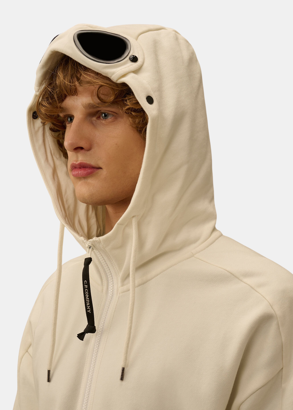 Zoom sur la capuche du sweat blanc cassé portée avec les verres noirs Goggle signature de la marque.