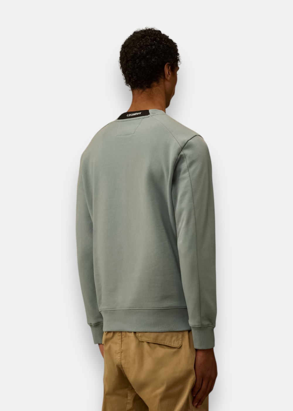 Vue de dos du sweat-shirt bleu gris porté, montrant le logo C.P. Company brodé au dos du col.