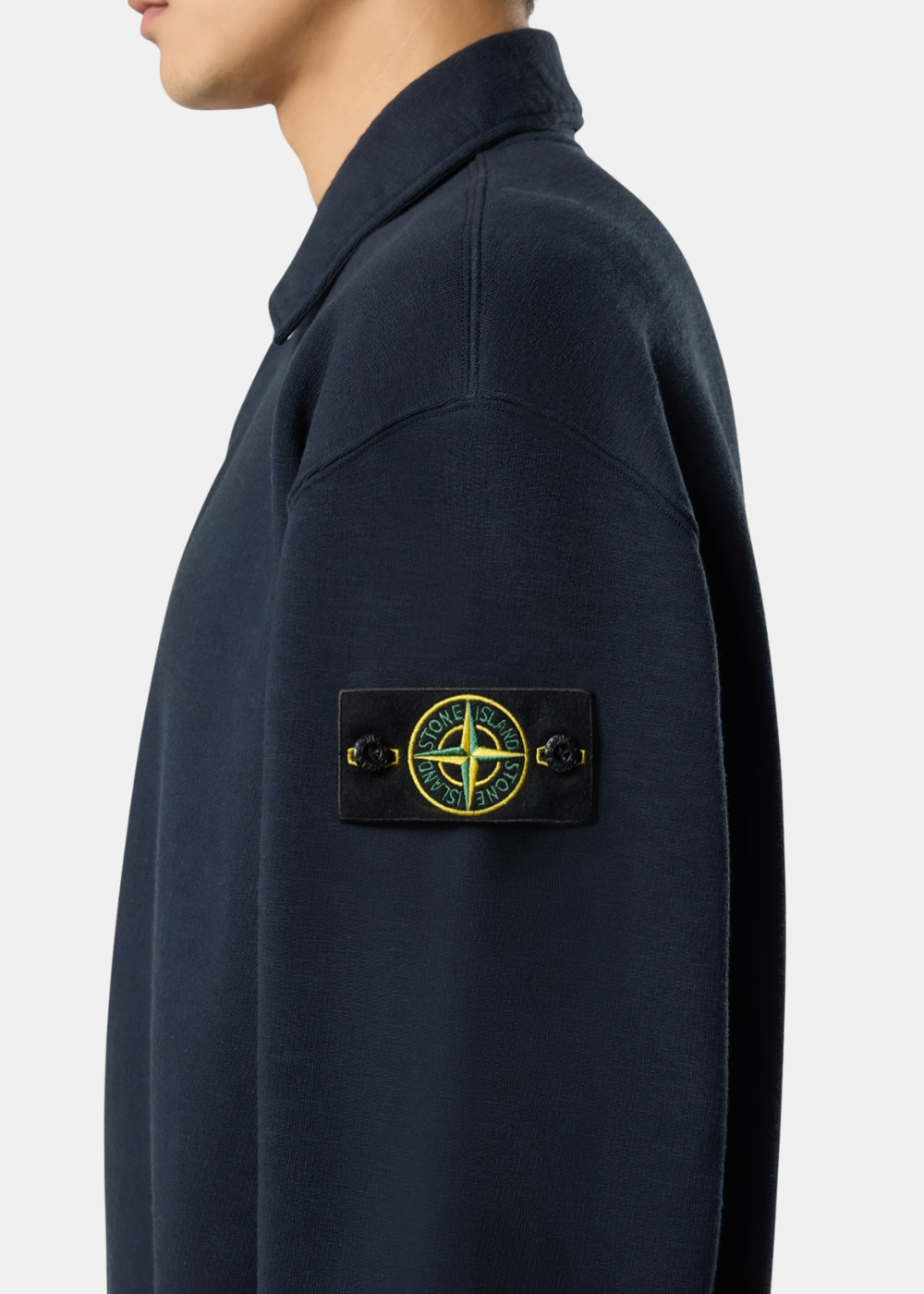 Gros plan porté sur la manche du sweat Stone Island bleu marine affichant le badge Compass