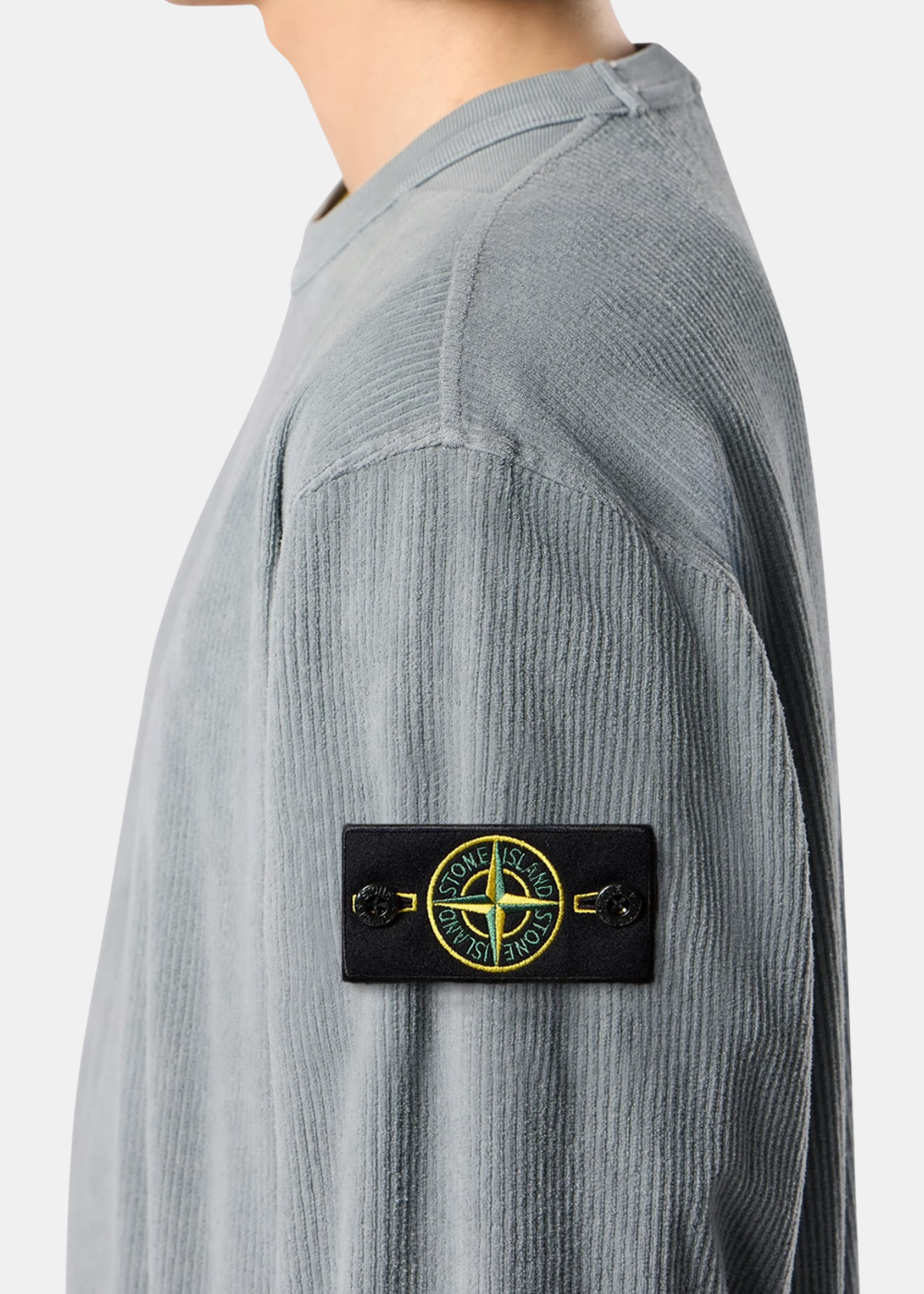 Gros plan sur le badge Compass Stone Island boutonné sur la manche d'un sweat en jersey velours côtelé gris porté
